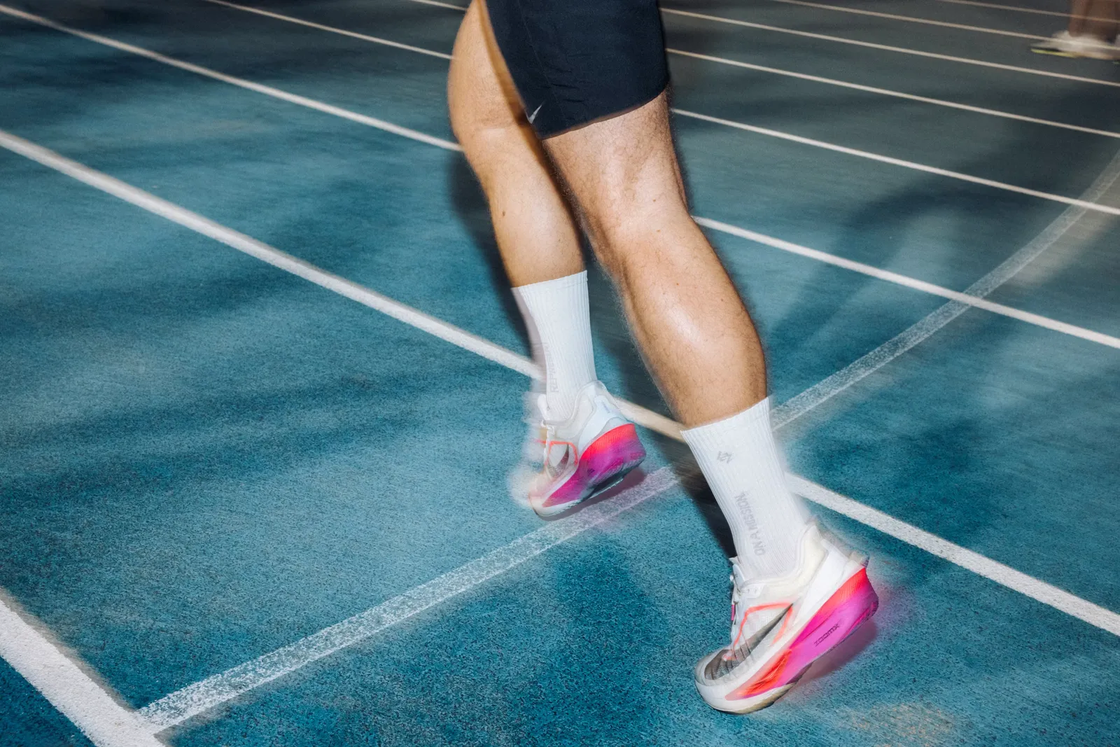 A runner mid-stride outdoors during a speed workout